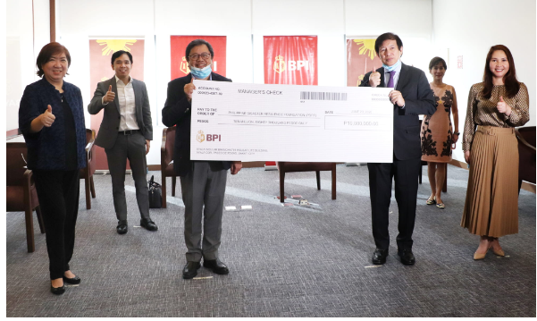 A photo of people doing a thumbs-up sign while holding a big check.